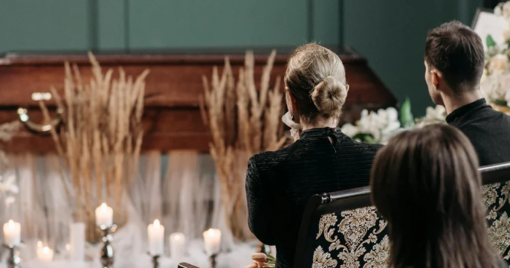 Pessoas em um velório, elas estão sentadas olhando para um caixão, representando os aspectos emocionais do direito das sucessões