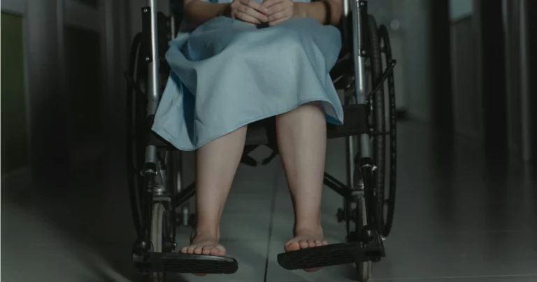 Mulher sentada em uma cadeira de rodas vestida com uma roupa hospitalar representando o conteúdo sobre a diferença entre auxílio-doença, aposentadoria por invalidez e auxílio-acidente