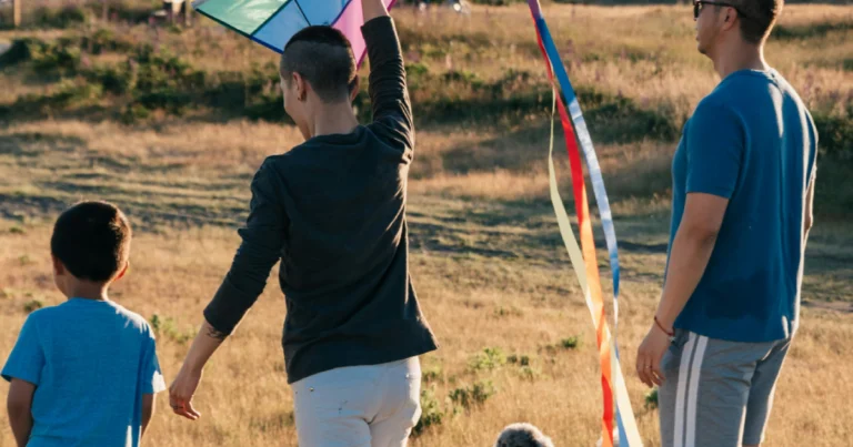Casal homoafetivo brincando com seu filho adotado com uma pipa para ilustrar o tema adoção por casais homoafetivos